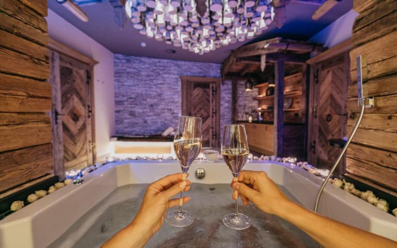 2 Personen mit einem Sektglas in der Hand im Whirlpool des Hotels Alpine Palace