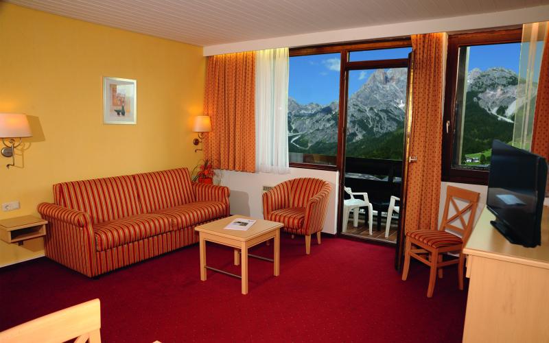 Blick in den Wohnbereich eines Doppelzimmers mit Balkon im Marco Polo Alpina Familien- und Sporthotel