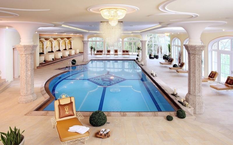 Innenpool mit Liegen, Säulen und großen Fenstern im Hotel Der Lärchenhof