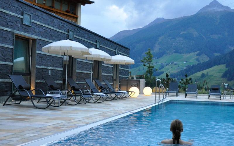 Eine Dame im Aussenpool mit Ruheliegen im Alpinhotel Jesacherhof