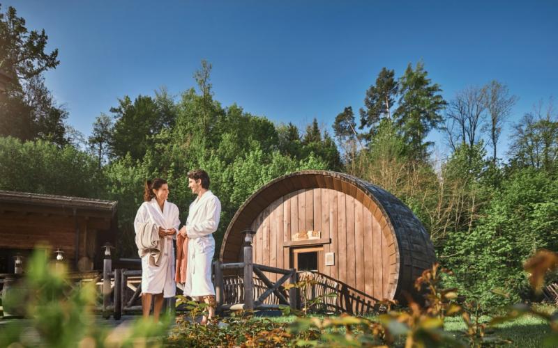 Zwei Gäste im Bademantel im Gartenbereich vor der Sauna des EurothermenResort Bad Schallerbach Hotel Paradiso