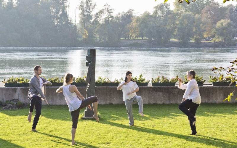 Mehrere Gäste beim TaiChi direkt am Wasser im Gesundheitshotel Gugerbauer