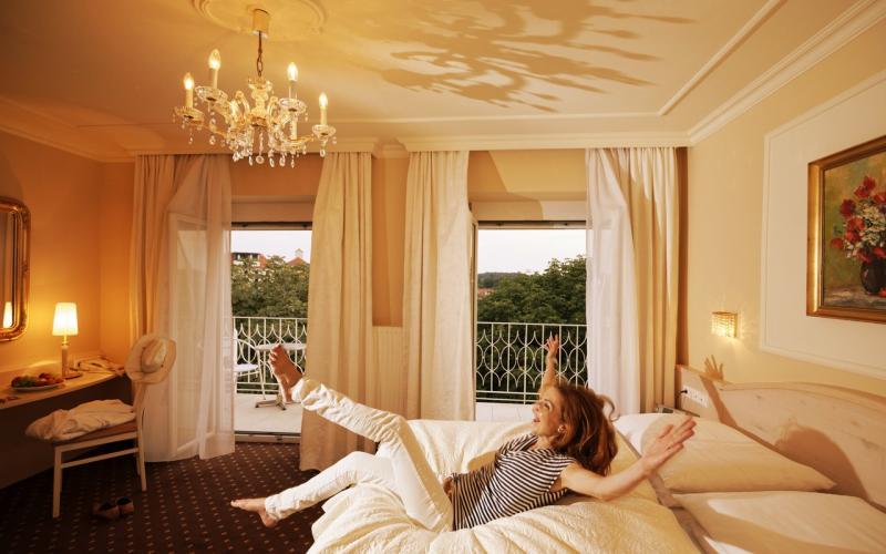 Eine Dame lässt sich im Hotel Stenitzer aufs Bett fallen