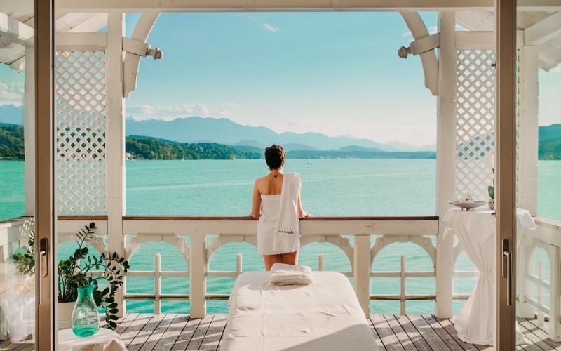 Eine Dame steht im Massagepavillon mit direktem Blick auf den See im Werzer´s Hotel Resort Pörtschach