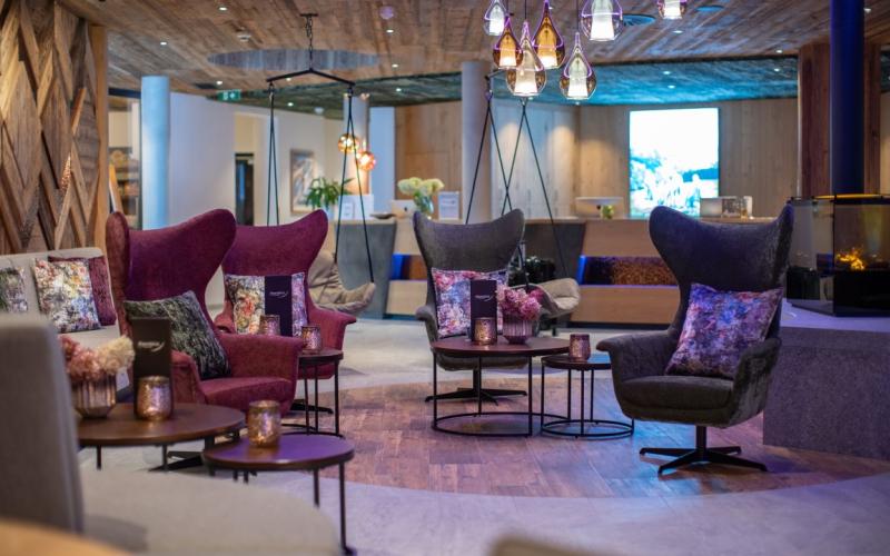 Blick in die Lounge mit unterschiedlichen Sitzmöglichkeiten und Hängesesseln im Sportresort Alpenblick