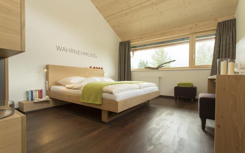 Modernes Doppelzimmer mit dem Schriftzug "Wahrnehmung" über dem Bett im Hotel Fischer am See ****