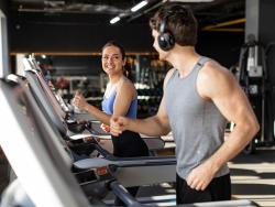 Ein junger mann und eine junge Frau trainieren nebeneinander auf Laufbändern