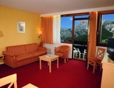 Blick in den Wohnbereich eines Doppelzimmers mit Balkon im Marco Polo Alpina Familien- und Sporthotel