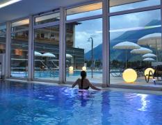 Eine Dame im Innenpool mit Blick auf den Aussenpool im Alpinhotel Jesacherhof bei Abendstimmung