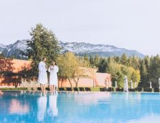 Paar steht mit Bademantel am Pool