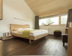 Modernes Doppelzimmer mit dem Schriftzug "Wahrnehmung" über dem Bett im Hotel Fischer am See ****