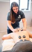 Ein Gast genießt eine Hot-Stone Behandlung durch eine Therapeutim im DAS WALCHSEE Sportresort