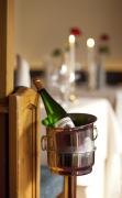 Eine Flasche Wein im Weinkühler im Restaurant mit gedeckten Tischen im Kulinarik und Genießerhotel Alpin