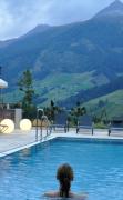 Eine Dame im Aussenpool mit Ruheliegen im Alpinhotel Jesacherhof