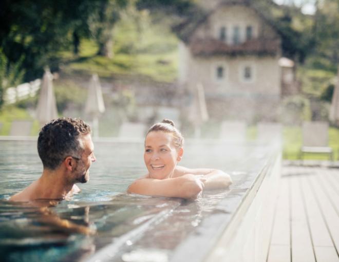 Zwei Gäste im Outdoor-Pool des DAS WALCHSEE Sportresorts